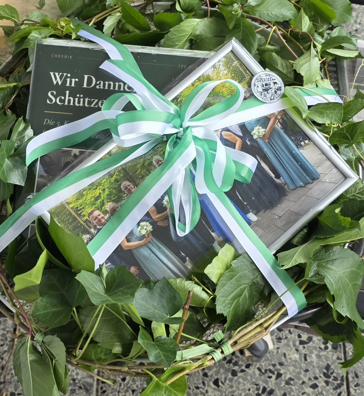 Geschenkkorb zum Jubiläum mit der Chronik „Wir Danner Schützen“ und einem gerahmten Thronfoto